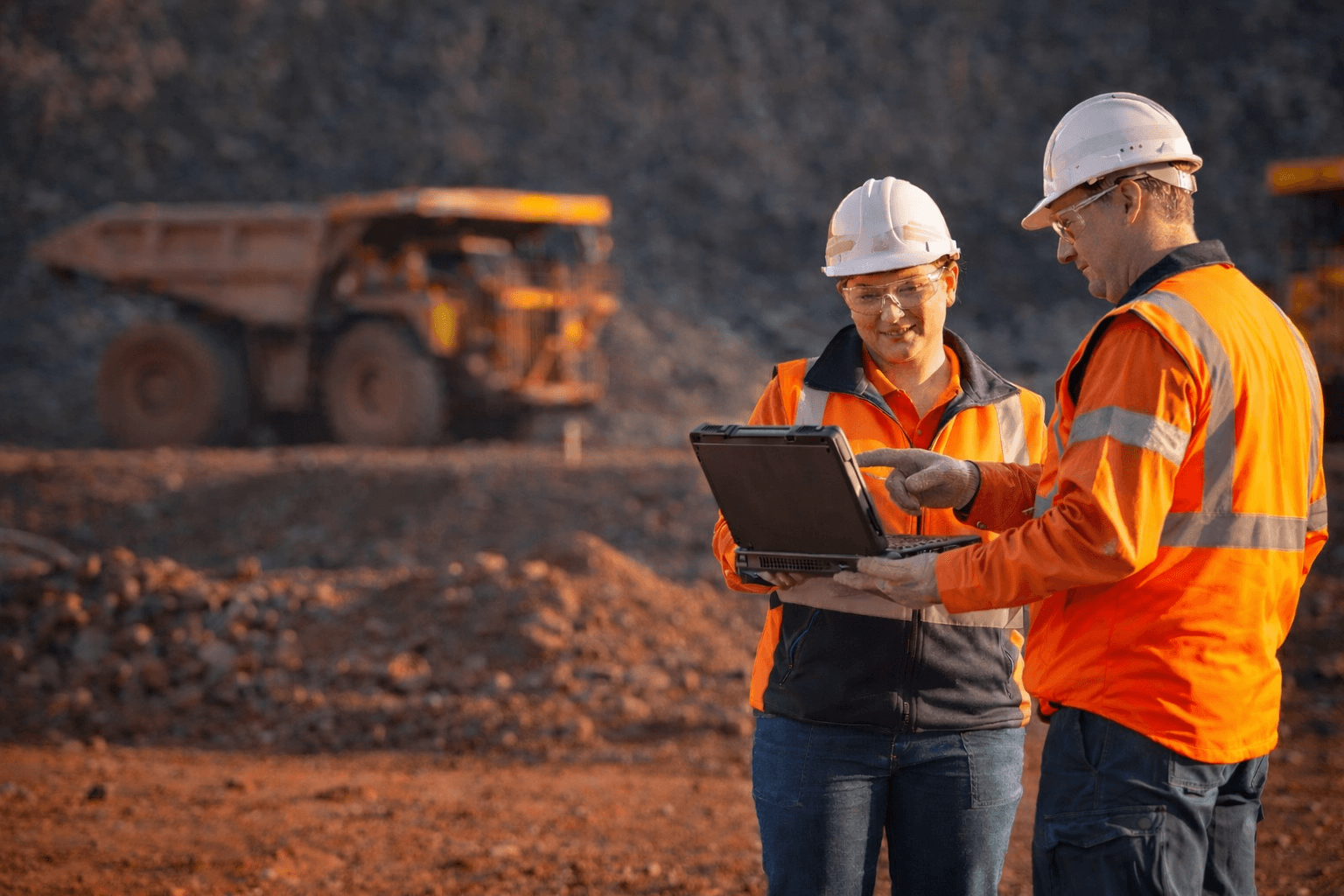 Two mining workers reviewing a rugged laptop on site